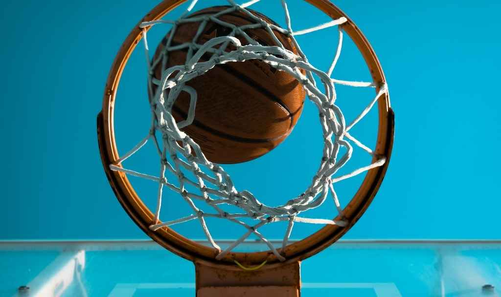 ballon de basket qui est en train de passer dans le panier, vue par-dessous